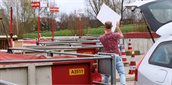 Verschillende containers op de milieustraat. Een man gooit een plank in een van de containers.