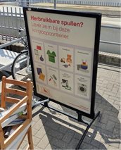 Stoepbord met de tekst: Herbruikbare spullen? Lever ze in bij deze kringloopcontainer. Daaronder staan getekende afbeeldingen van bijvoorbeeld keukenspullen, speelgoed en gereedschap.